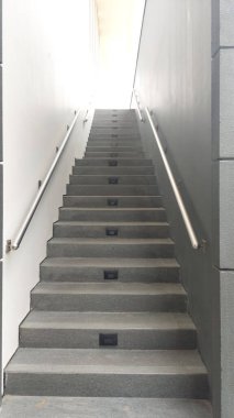 Üst taraftaki parlak ışıkla aydınlatılan metal parmaklıklı çağdaş gri taş merdiven görüntüsü. Yükselme, gelecek, ilerleme.