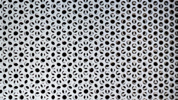 Yuvarlak delikli paslı gümüş metal arka plan. Delikli metal doku. Demir grisi delinmiş arka plan. Çelik dayanıklı malzeme. Duvarın içinde daireler. Makro