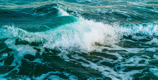 Muhteşem turkuaz dalgalar ve beyaz köpük. Dalgalar kıyıya çarpıyor. Mavi deniz suyu. Bir tatil köyü için canlı bir deniz manzarası.
