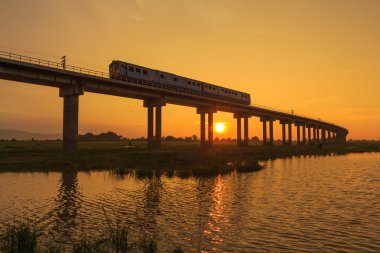 Bir tren Köprüsü günbatımı zamanı geçiyor