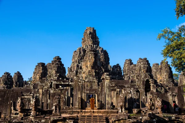 I monaci nelle antiche facce di pietra del tempio Bayon, Cambogia Foto Stock Royalty Free