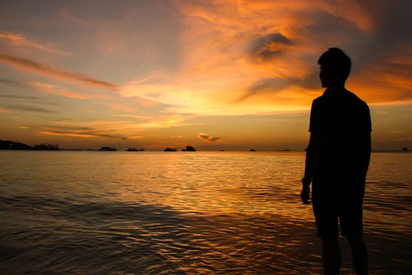 Silhouette di uomo al tramonto sulla spiaggia Fotografia Stock