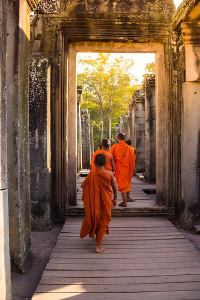 I monaci nelle antiche facce di pietra del tempio di Bayon, Angkor Foto Stock Royalty Free