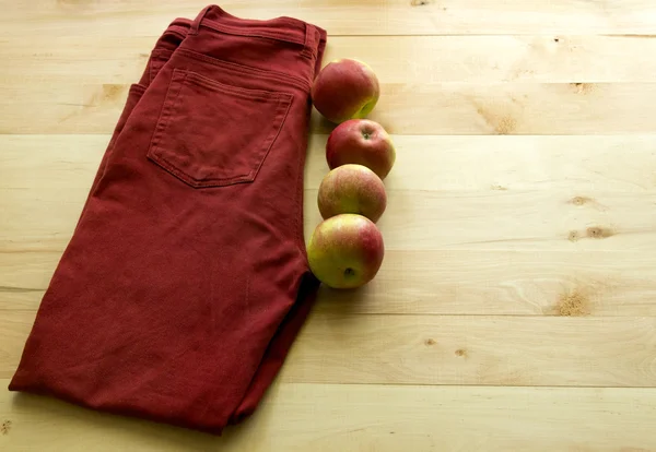 Kırmızı kot pantolon ve ahşap arka plan üzerinde elma. Diyet kilo kaybı için.