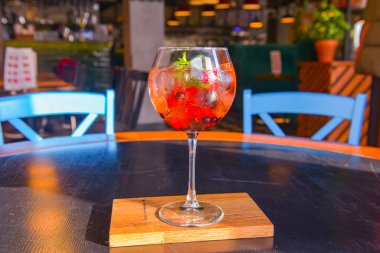 Buzlu ve dutlu ahududu kokteyli. İçi böğürtlenli taze kokteyl. Siyah ahşap masada uzun bir şarap kadehinde servis edilen nefis alkol içeceği. Bulanık restoran geçmişi.