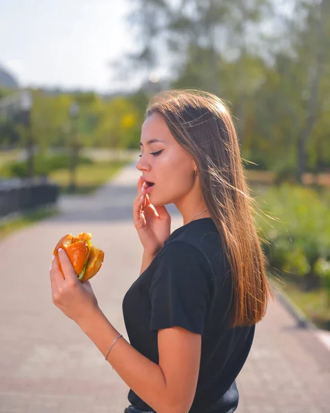 여자가 햄버거와 감자튀김을 먹으면서 있습니다 아름다운 코카서스 모델이 햄버거를 있습니다 — 스톡 사진