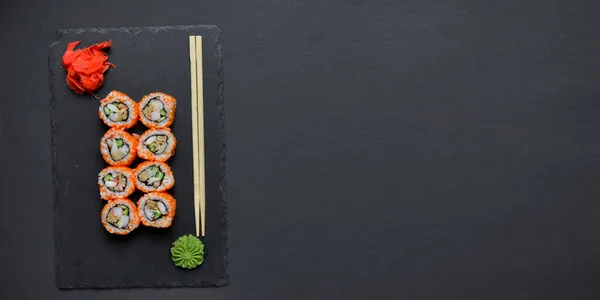 Different Sushi rolls, sushi set rolled in cheese. California philadelphia sushi rools served on a black chalk board. Japanese cuisine concept. Copy space banner.