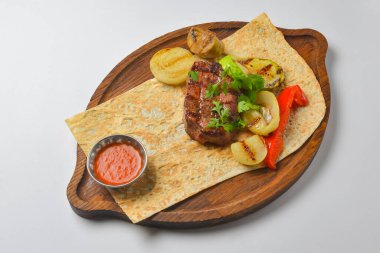 Beyaz arka planda servis edilen lahanalı ekmek ve soslu Türk ve Arap usulü ızgara biftek ve ızgara sebze. Gürcistan mutfağı kavramı.