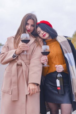 Dışarıda şarap bardakları olan iki hoş ve neşeli kadın. Boş zaman, durgun hayat, dışarıda yeme konsepti..
