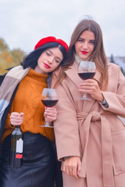 Dışarıda şarap bardakları olan iki hoş ve neşeli kadın. Boş zaman, durgun hayat, dışarıda yeme konsepti..