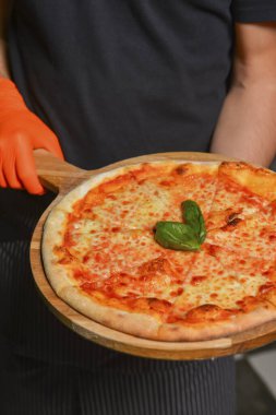 Margarita pizzası tahtada. Restoranda ya da lokantada pizza servisi yapan garson, dışarıda yemek konsepti, işte garson. Fast food, abur cubur kavramı.