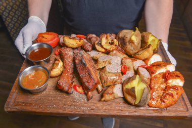 Lezzetli karışık ızgara tabağı yakın çekim. Et, biftek, sosis, restoranda ya da lokantada servis edilen patates. Garson servisi, dışarıda yemek konsepti. Yemek için lezzetli bir fikir..