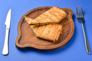 Lavaş ve suluguni peyniri. Lezzetli çerez. Mavi arka planda ahşap bir tahtada servis edilmiş. Kapat..