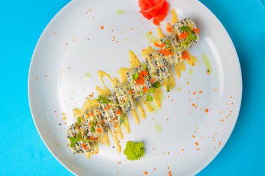 Suşi seti: Mavi arka planda sashimi ve suşi. Geleneksel Japon mutfağı konsepti, yakın çekim. Beyaz yuvarlak tabakta lezzetli suşi ruloları..