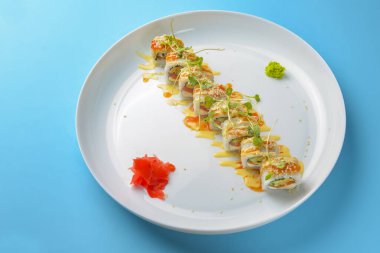 Suşi seti: Mavi arka planda sashimi ve suşi. Geleneksel Japon mutfağı konsepti, yakın çekim. Beyaz yuvarlak tabakta lezzetli suşi ruloları..