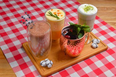 Farklı bardaklarda çeşitli süt menüleri için. Soğuk sonbahar ya da kış havası için Hor içkileri, sonbahar mevsimi. Meyve çayı, kakao içeceği, kibrit latte, kırmızı ekose masa örtüsü üzerine hurma çayı..