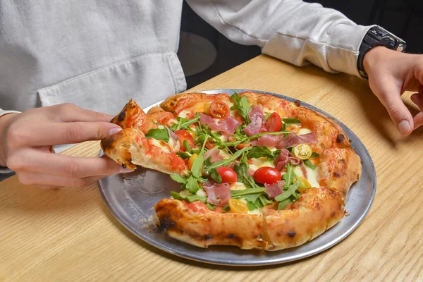 Young man eating a slice of pizza margherita. Still life, eating out concept. At restaurant or at home, pizza delivery, close up on pizza.