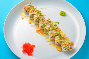 Suşi seti: Mavi arka planda sashimi ve suşi. Geleneksel Japon mutfağı konsepti, yakın çekim. Beyaz yuvarlak tabakta lezzetli suşi ruloları..