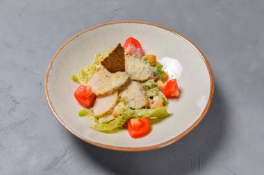 Bir kase Sezar Salatası restoranda ya da lokantada siyah arka planda servis edildi. Geleneksel Sezar tarifi. Konsepti tüketiyorum.