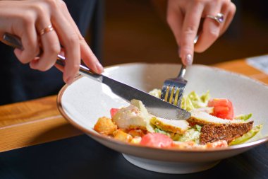 Genç bir kadın, restoranda ya da lokantada geleneksel tarifli sezar salatası yer. Konsepti yemek, akşam yemeği fikri....