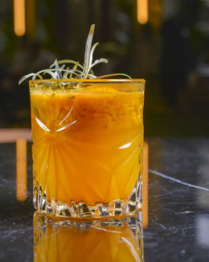 Elma suyu, buz ve tarçınlı kokteyl siyah bir masada küçük bir bardakta. Restoran konseptinde dışarıda yemek yemek. Parti için nefis alkol içecekleri..