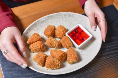 Kızarmış camembert peyniri ve kızılcık sosu beyaz tabakta servis ediliyor. Çatal ve bıçakla peynir yemek. Sakin bir hayat, restoran konseptinde yemek yemek..