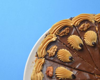 Üstü kremalı çikolatalı pasta ve fındıklı renkli arka plan. Çay ya da kahve saati için lezzetli çikolatalı pasta..