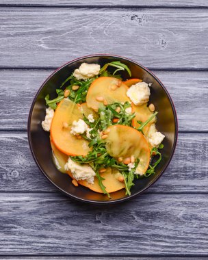 Arugula salatası, hurma, kırsal ahşap arka planda beyaz peynir. Akşam yemeği için sağlıklı karışık salata. Kapat..