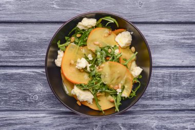 Arugula salatası, hurma, kırsal ahşap arka planda beyaz peynir. Akşam yemeği için sağlıklı karışık salata. Kapat..