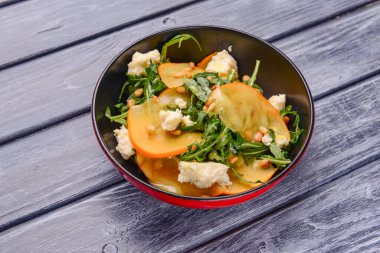 Arugula salatası, hurma, kırsal ahşap arka planda beyaz peynir. Akşam yemeği için sağlıklı karışık salata. Kapat..