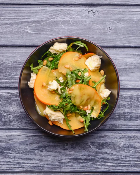 Arugula salatası, hurma, kırsal ahşap arka planda beyaz peynir. Akşam yemeği için sağlıklı karışık salata. Kapat..