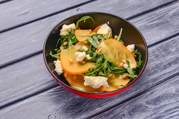 Arugula salatası, hurma, kırsal ahşap arka planda beyaz peynir. Akşam yemeği için sağlıklı karışık salata. Kapat..