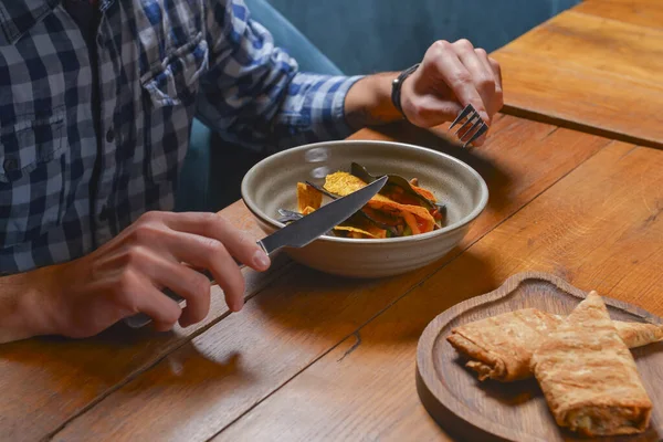 Young man eating salad in restaurant or diner. Georgian cuisine restaurant concept. Vegetable salad with lavash roll. Still life, eat with knife and fork.