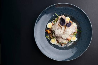 Haşlanmış yumurta ve parmesan peynirli İtalyan makarnası. Siyah arka planda mavi bir tabakta servis edilmiş. Akşam yemeği fikri, İtalyan mutfağı konsepti..