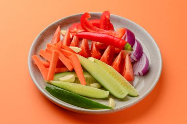 Bir tabak taze sebze dilimi. Sağlıklı çiğ sebze salatası. Turuncu arka planda. Sağlıklı yemek..