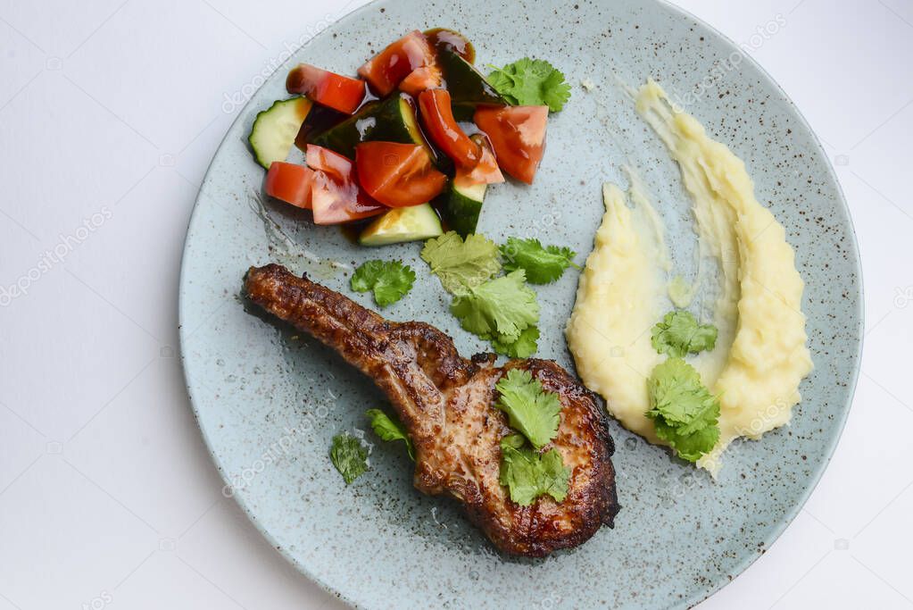 Barbecue Tomahawk Steak with mashed potatoes and vegetables. Served on a blue plate over white background. Delicious idea for dinner.