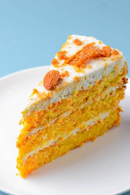 A piece of coconut vanilla cake on blue background. Sweet dessert for tea or coffee time. Close up.