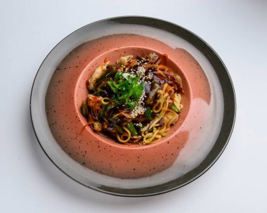 Kızarmış tavuk ve sebzeli Asya tavası, beyaz arka planda servis edilen beyaz seramik tabakta tava salatası. Asya mutfağı kavramı, dışarıda yemek..