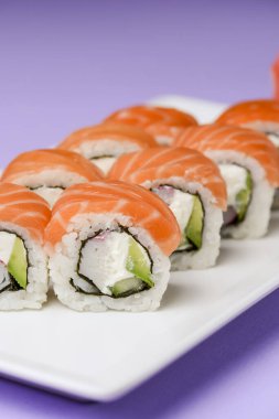 Maki Suşi, füme somon ve krem peynirden yapılmış rulo. Geleneksel Japon mutfağı konsepti, pastel mor arka plan üzerinde. Geleneksel tarif.