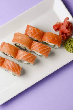 Maki Suşi, füme somon ve krem peynirden yapılmış rulo. Geleneksel Japon mutfağı konsepti, pastel mor arka plan üzerinde. Geleneksel tarif.