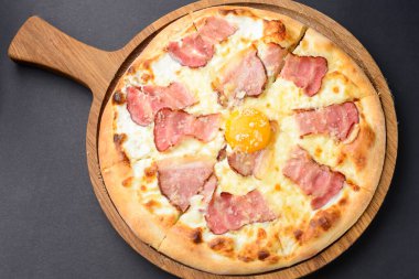 Pastırmalı pizza ve yumurta sarısı. Siyah arkaplan üzerinde geleneksel tarif.