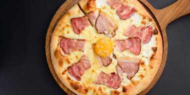 Pastırmalı pizza ve yumurta sarısı. Siyah arkaplan üzerinde geleneksel tarif.