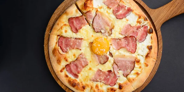 Pastırmalı pizza ve yumurta sarısı. Siyah arkaplan üzerinde geleneksel tarif.