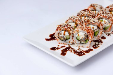 Yılanbalığı ve unagi soslu Japon suşisi seti. İçinde krem peynir var. Beyaz arka planda beyaz bir tabakta servis edilmiş. Geleneksel tarif.