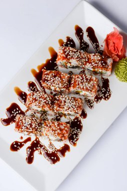 Yılanbalığı ve unagi soslu Japon suşisi seti. İçinde krem peynir var. Beyaz arka planda beyaz bir tabakta servis edilmiş. Geleneksel tarif.