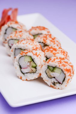 Maki Suşi, füme somon ve krem peynirden yapılmış rulo. Geleneksel Japon mutfağı konsepti, pastel mor arka plan üzerinde. Geleneksel tarif.