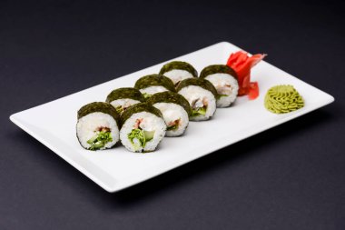 Maki Suşi, füme somon ve krem peynirden yapılmış rulo. Geleneksel Japon mutfağı konsepti, siyah arka planda. Geleneksel tarif.