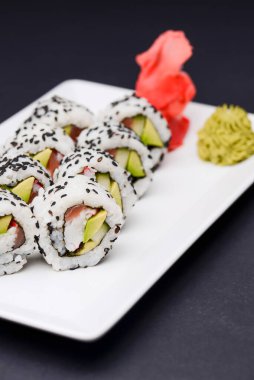 Maki Suşi, füme somon ve krem peynirden yapılmış rulo. Geleneksel Japon mutfağı konsepti, siyah arka planda. Geleneksel tarif.