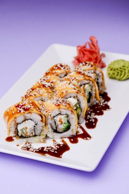 Mor arka planda beyaz bir tabakta sunulan unagi soslu yılan balığı, somon balığı ve ton balığı. Geleneksel Japon mutfağı, Asya mutfağı kavramı.