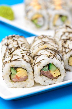 Suşi büyük seti mavi arka planda beyaz bir tabakta servis edilir. Geleneksel Asya Japon mutfağı konsepti, kapatın..